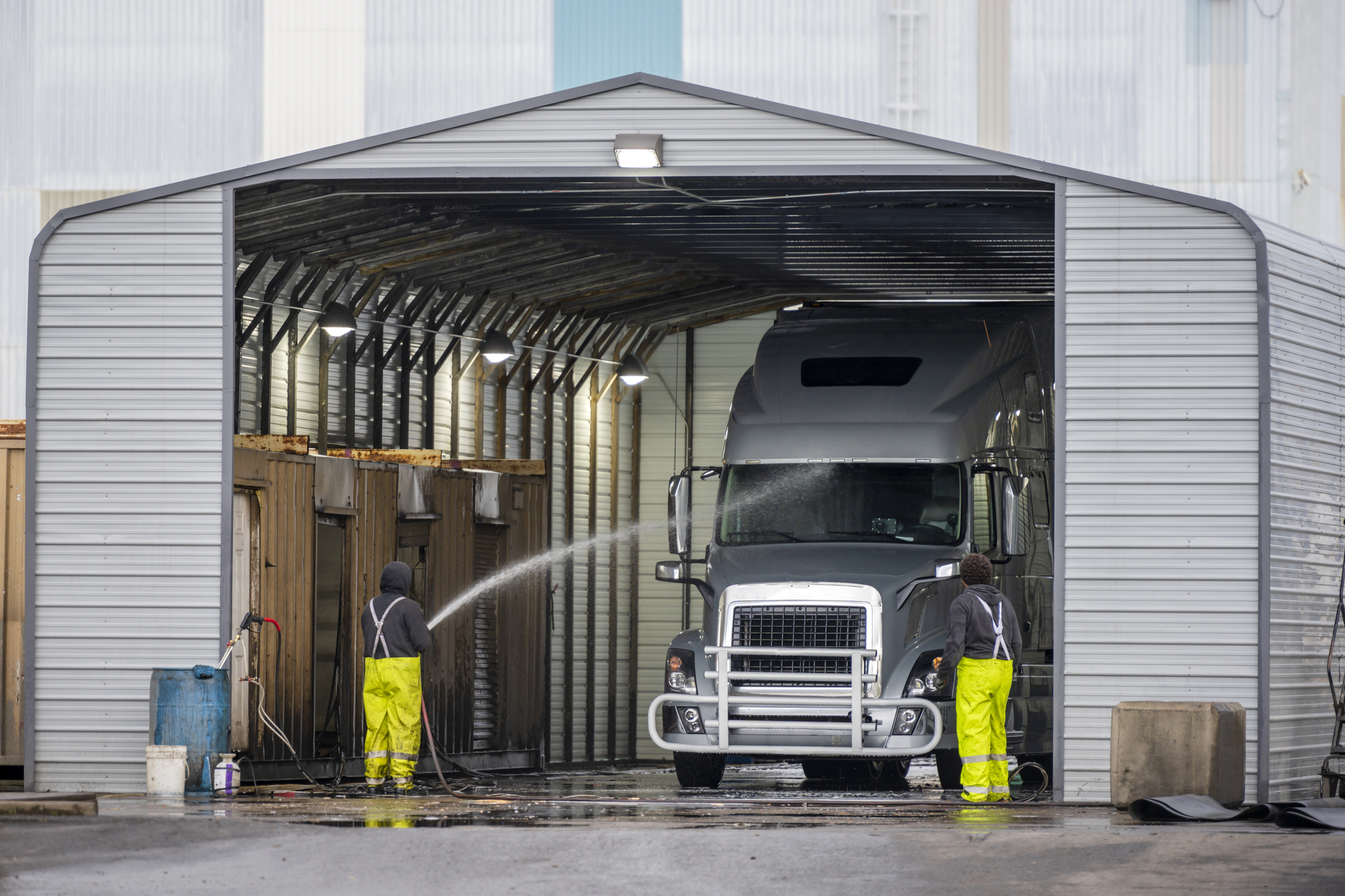 Big rig semi truck washes in covered car wash station with manual washing