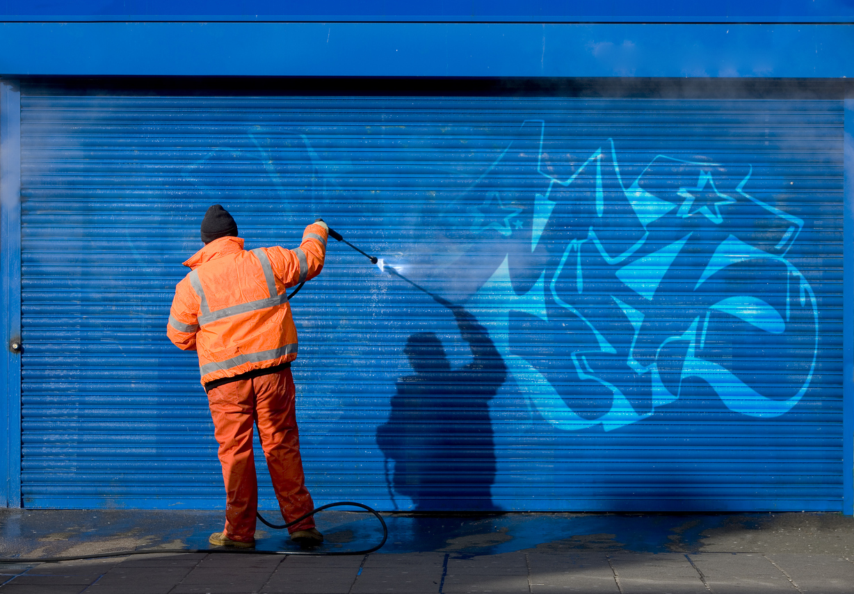 Washing graffiti off a security grill.