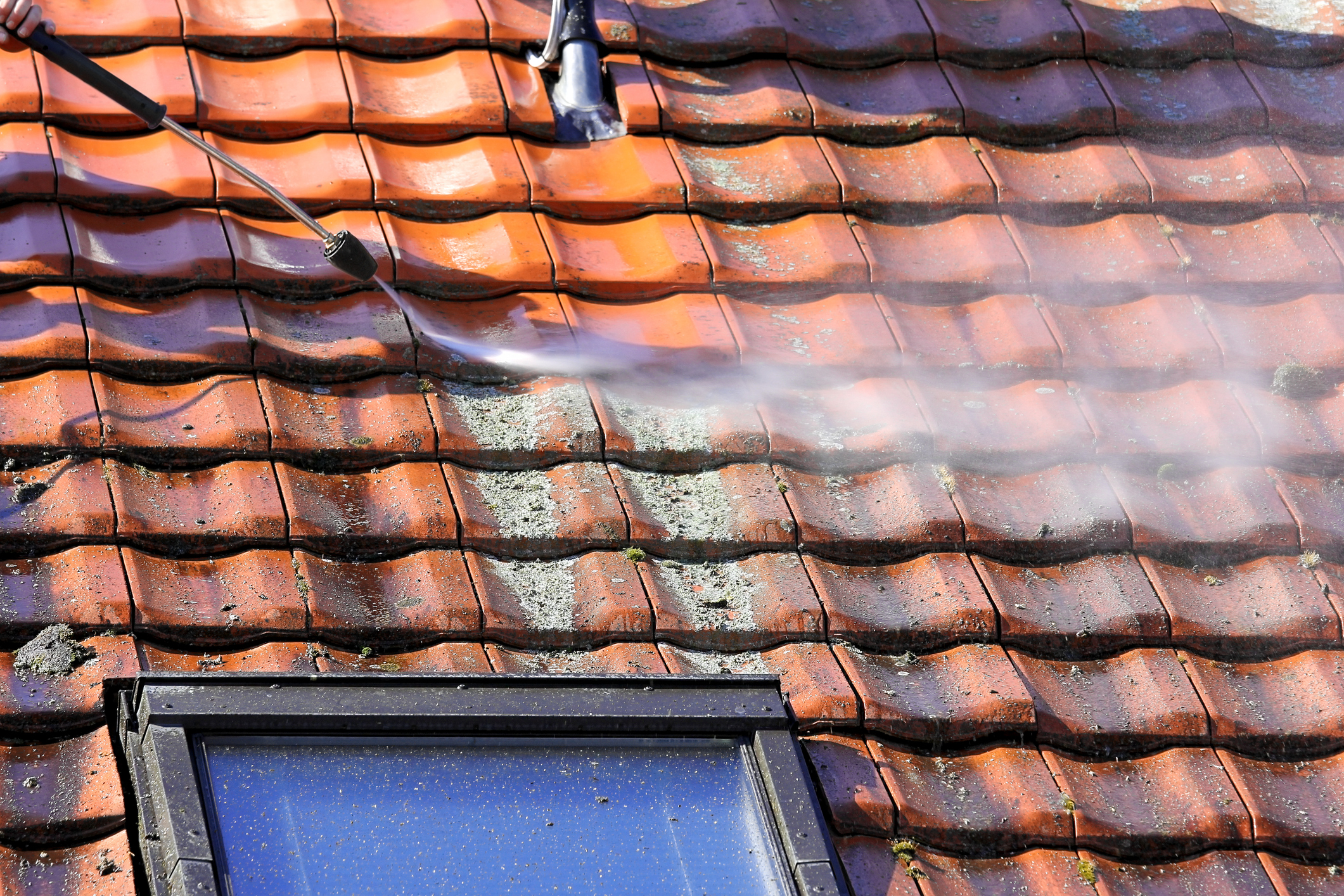 Worker is cleaning the roof and rainwater gutter with high pressure.